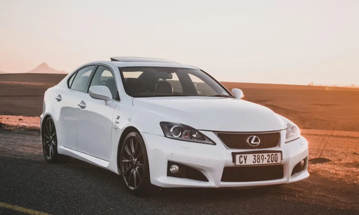 White Lexus IS parked on road at sunset.